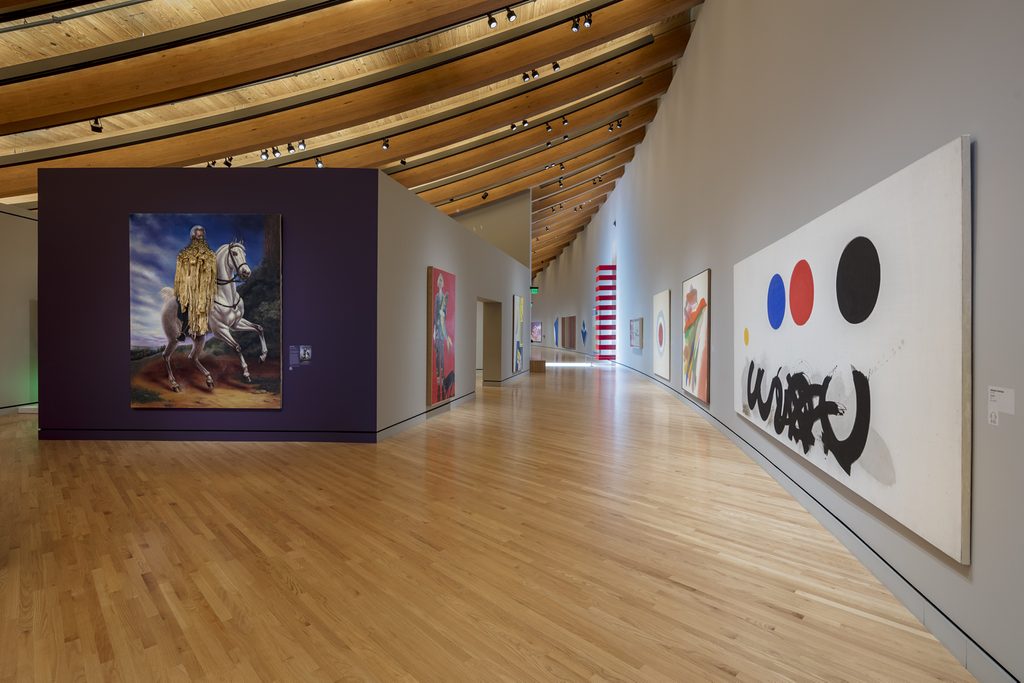 Art gallery corridor with wooden ceiling, polished floor, modern abstract and figurative paintings.