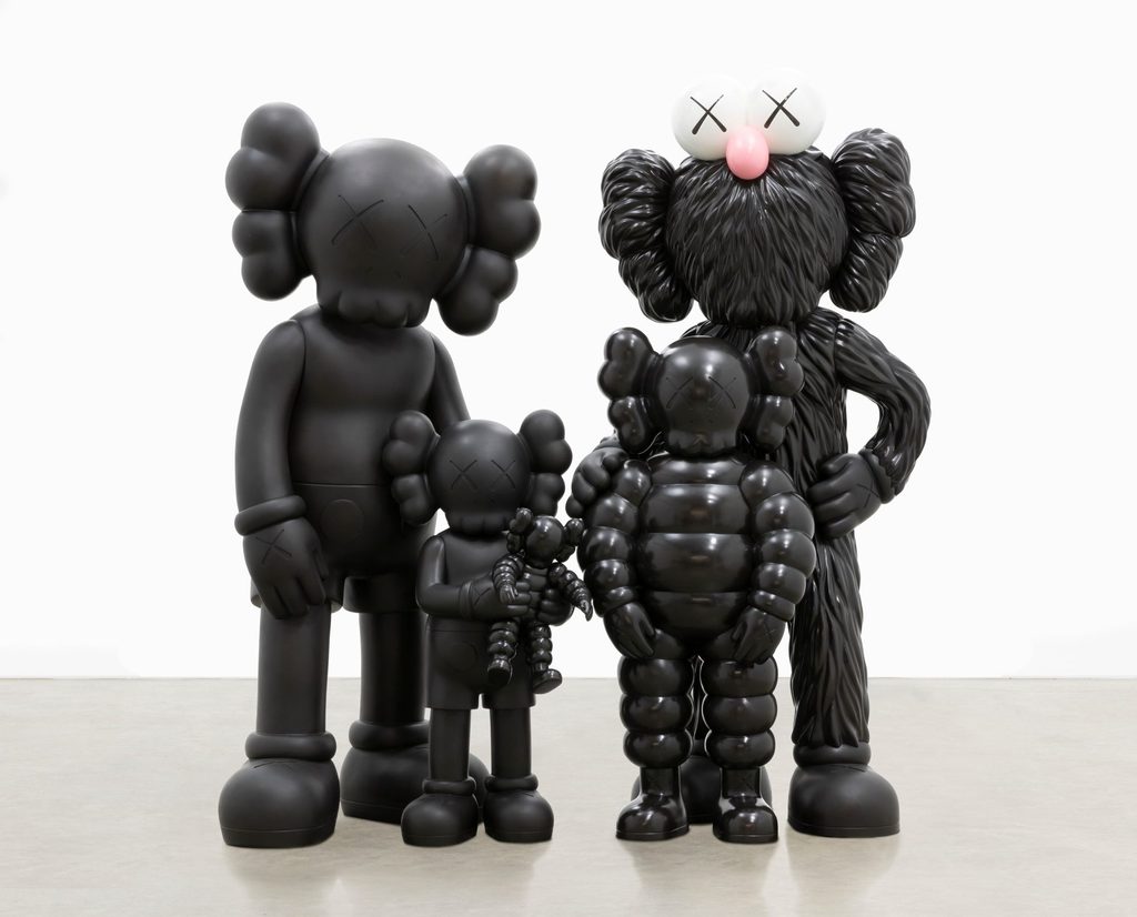 Cuatro esculturas negras, del artista KAWS, que representan una familia.