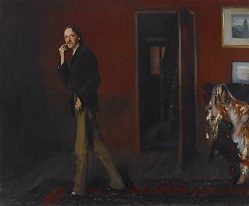 Man in dim room with red walls, near open door; chair with colorful fabrics on right