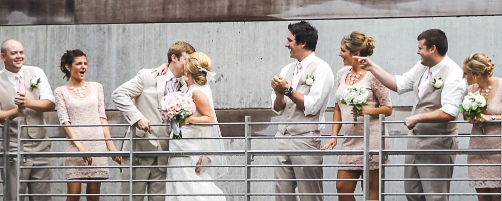 Wedding Venue Wedding party in formal attire on metal railing with pink ties and dresses, holding bouquets.