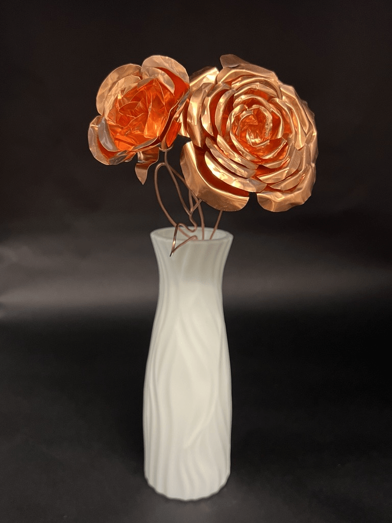 White vase with metallic copper-like flowers on a dark background.