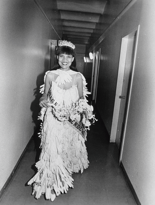 Black and white photograph of smiling woman in a white dress with a crown